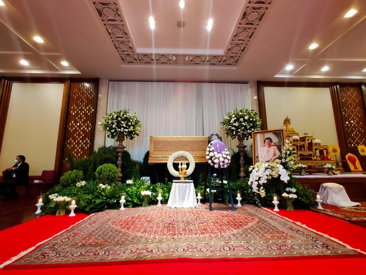 Elegant ceremony hall with white floral arrangements and gold casket
