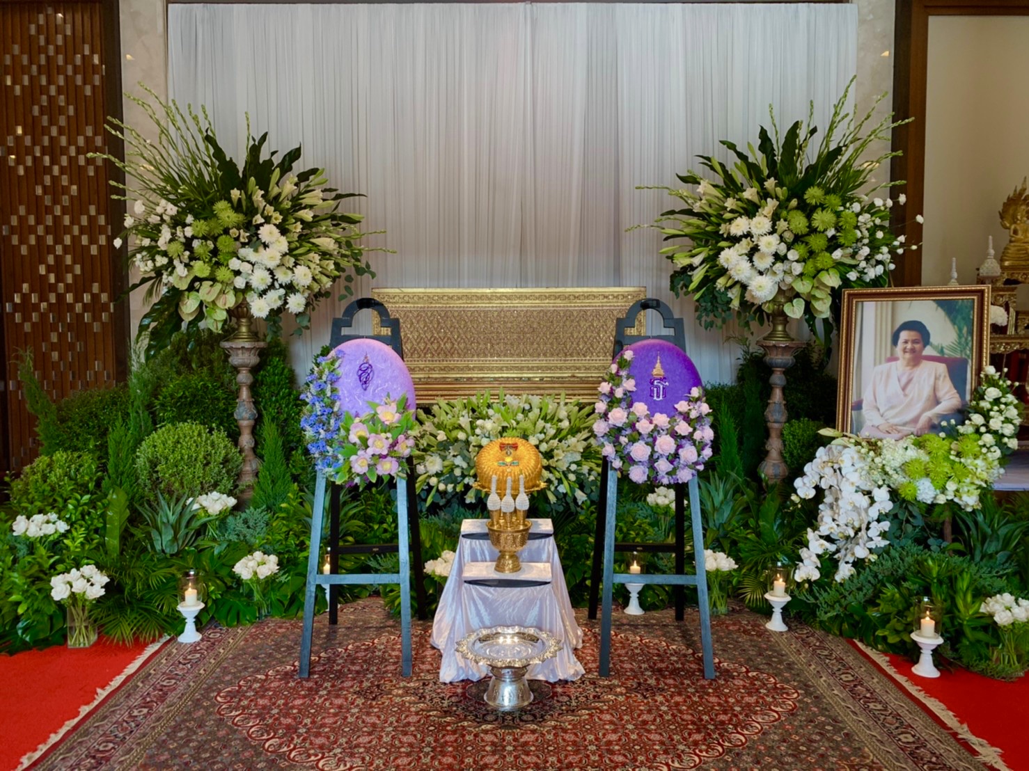 Full ceremony hall with royal cremation wreaths and greenery