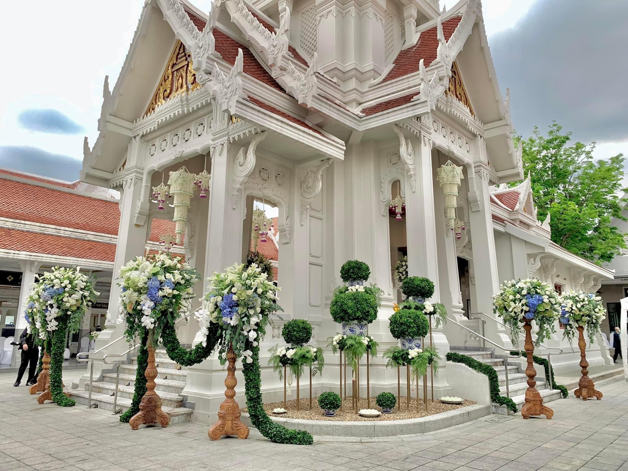 White royal temple exterior with green topiary and white flower arch